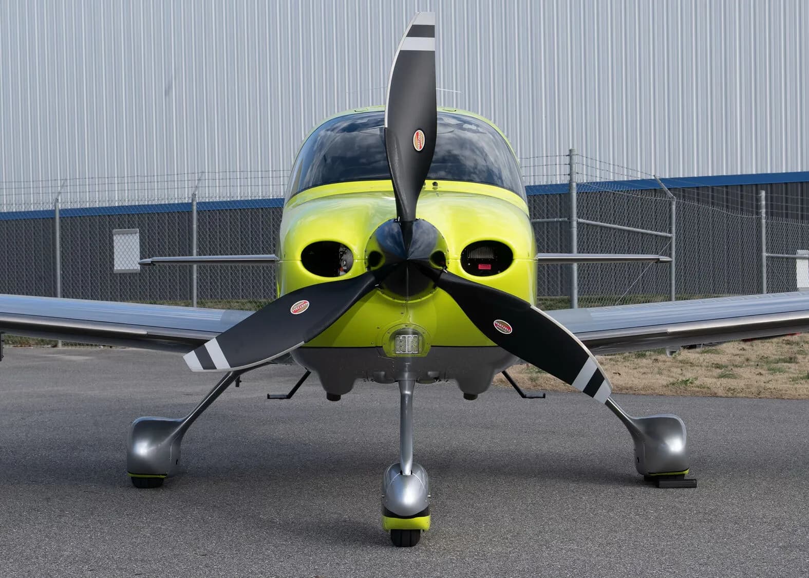 A direct front view of the yellow and silver Cirrus SR22, N772RG, showing its propeller and landing gear.