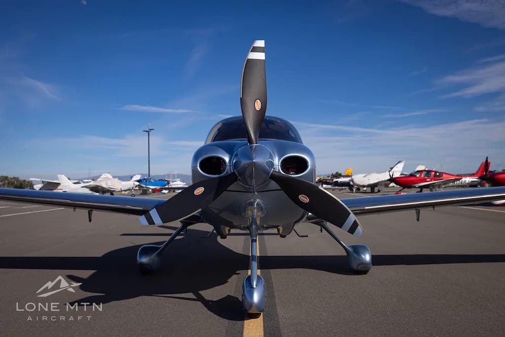 Head-on view of a silver Cirrus SR22 aircraft, N512HW, showing its propeller and nose on an airfield.