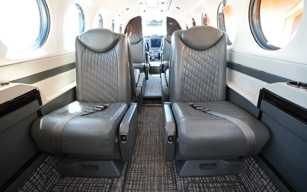 The spacious aircraft cabin interior with multiple rows of grey quilted leather seats and large windows.