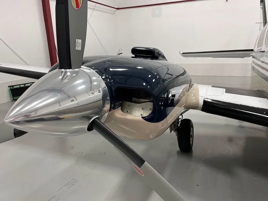 A close-up view of the aircraft's dark blue engine cowling, polished propeller spinner, and propeller blade.