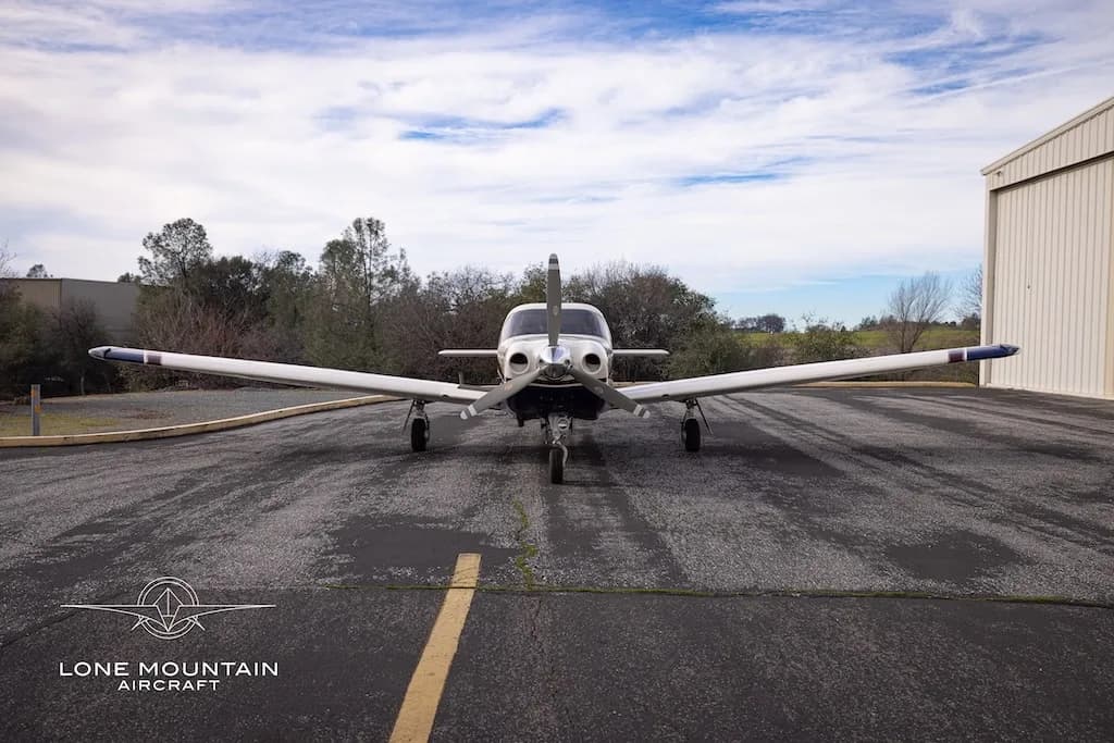 A head-on view of the Piper Saratoga II TC aircraft (N92LL) with blue and white paint scheme parked on an asphalt apron.