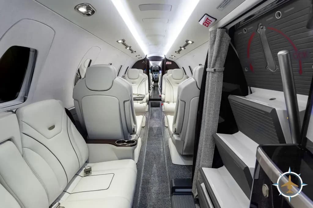 The aircraft cabin interior with white leather seats and an aisle leading to the rear.