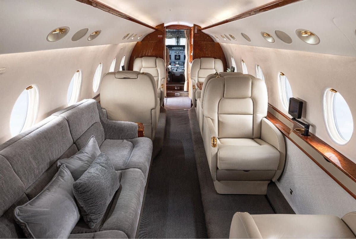Aircraft cabin featuring a sofa and leather seats.