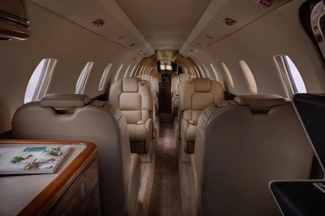 Aircraft interior with leather seats and carpeted floor.