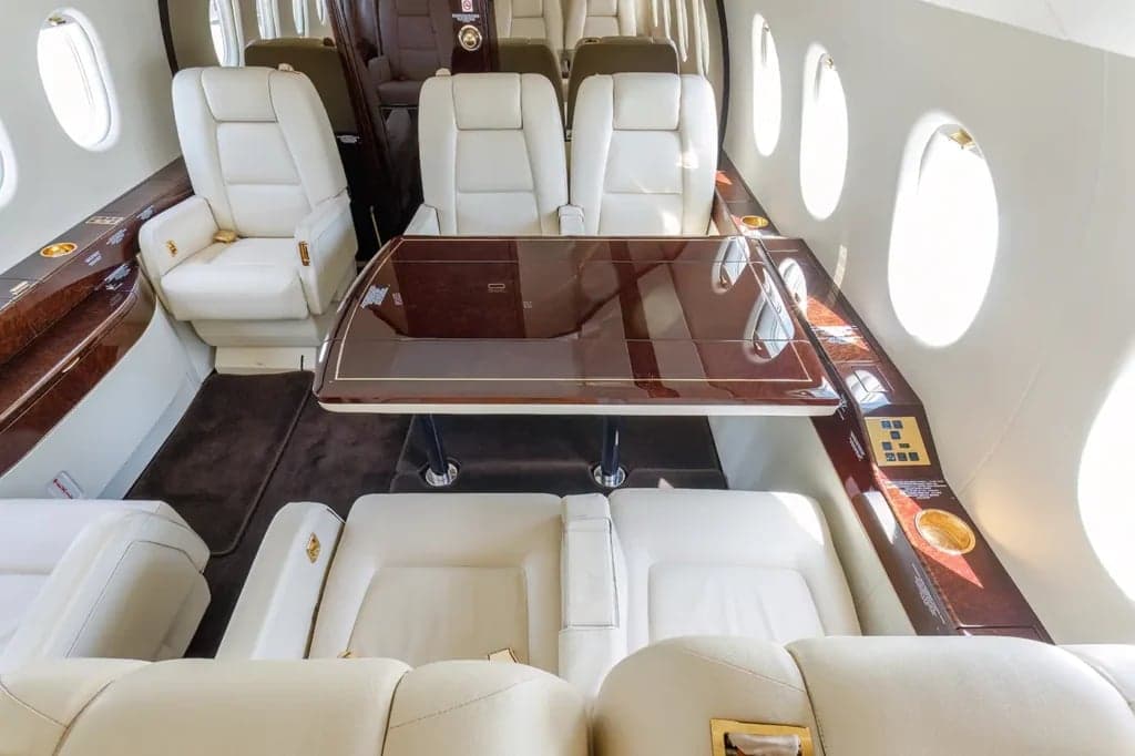 A view of the aircraft cabin with white leather seats and a table.