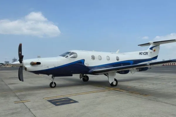 A white and blue Pilatus PC-12 aircraft with registration HC-CZK parked on an airport tarmac with its propeller visible.