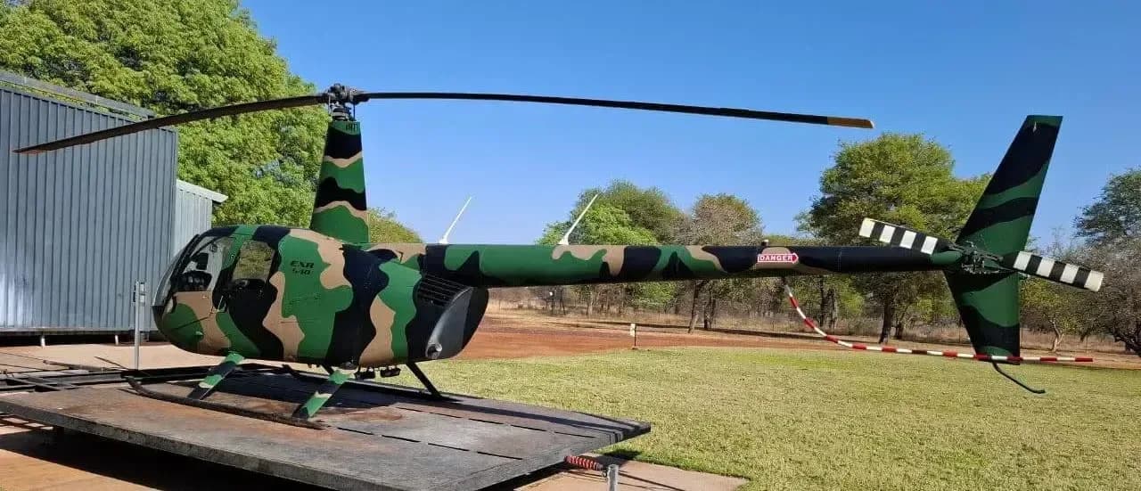 Robinson R-40 helicopter with camouflage paint scheme parked on a platform.