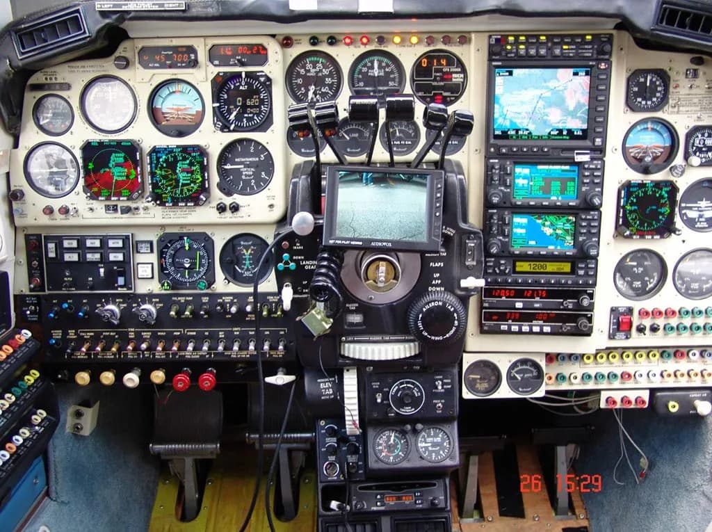 A detailed view of an aircraft cockpit instrument panel with multiple gauges, screens, and controls.