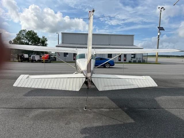 Rear view of the N75926 aircraft parked on an asphalt tarmac in front of a hangar.