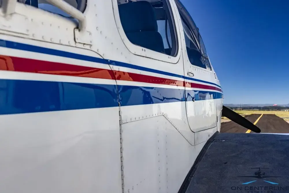 Close-up of the side of the aircraft with blue and red stripes, parked on the tarmac.