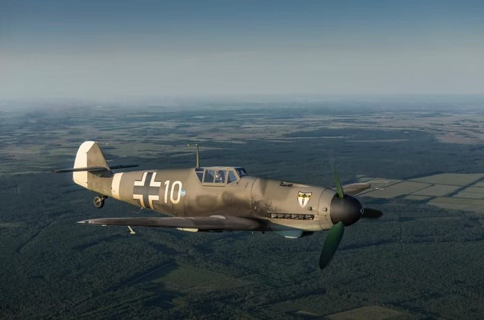 A gray Messerschmitt Bf 109 aircraft in flight.
