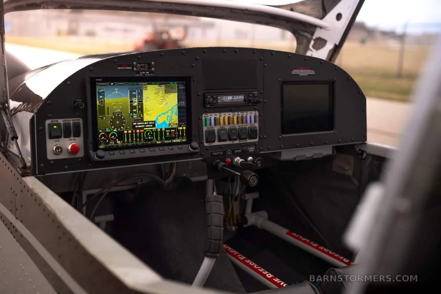 A close-up view of the aircraft's cockpit, featuring a glass panel display with navigation information and various switches.