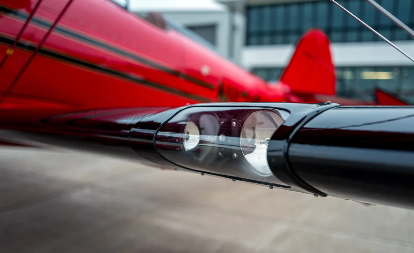 Close up of the wingtip navigation light on a red biplane.