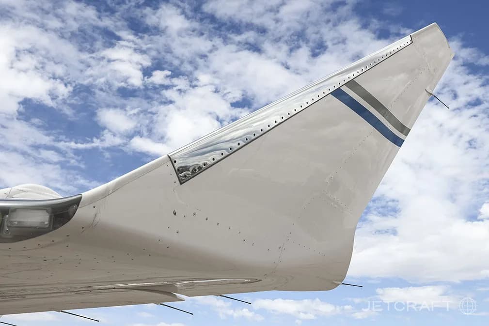 A close-up view of the wingtip of a white Bombardier Global 6000 business jet, showing blue and grey stripes.