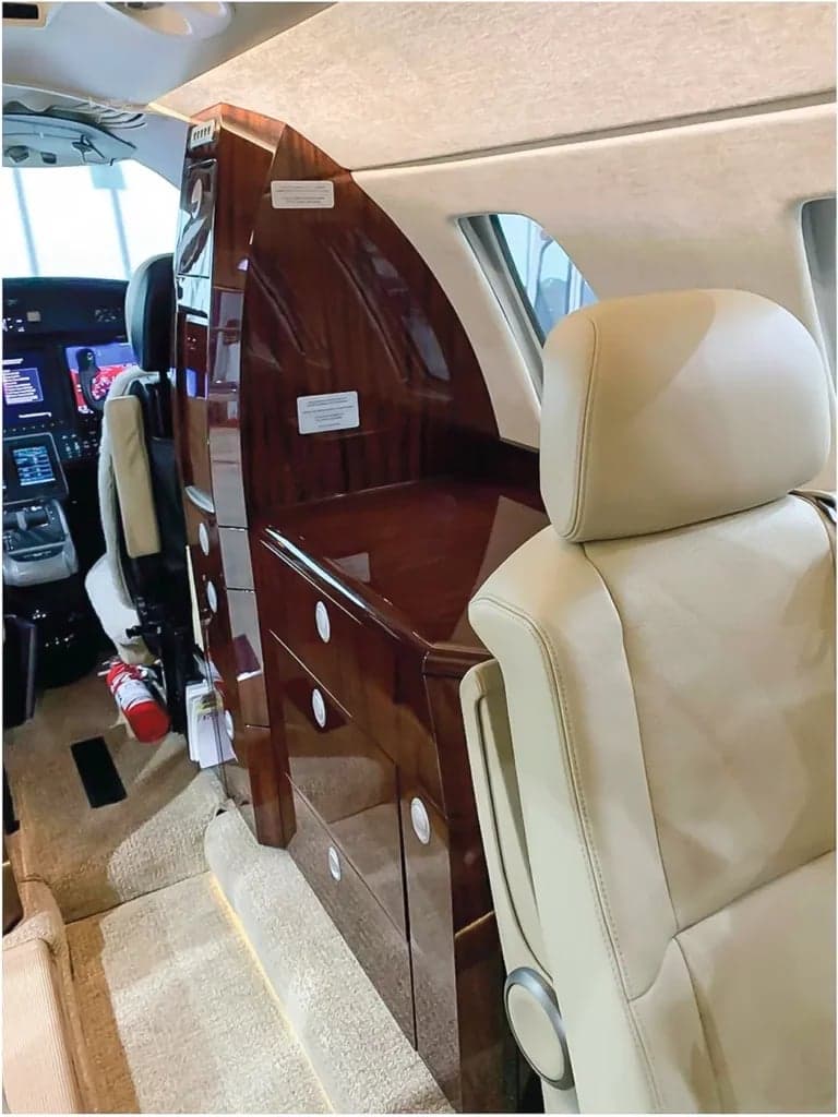 The aircraft's interior features a wooden cabinet and tan leather seats.