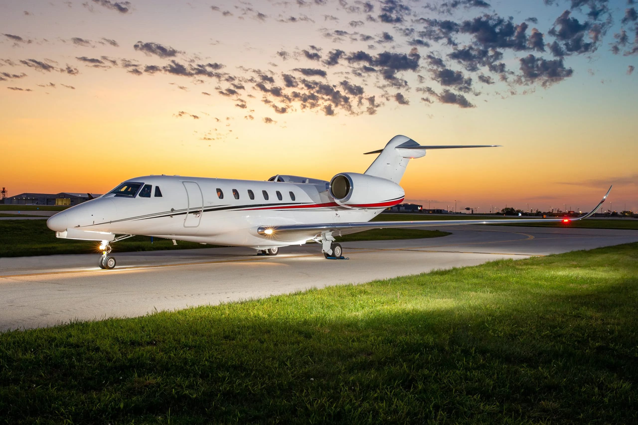 A Citation CJ4 aircraft is parked on the tarmac at sunset.