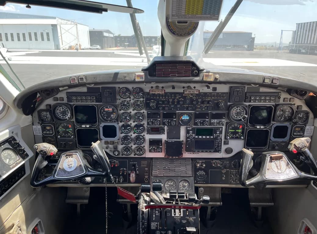 A detailed view of a complex aircraft cockpit with numerous analog gauges, screens, and controls.