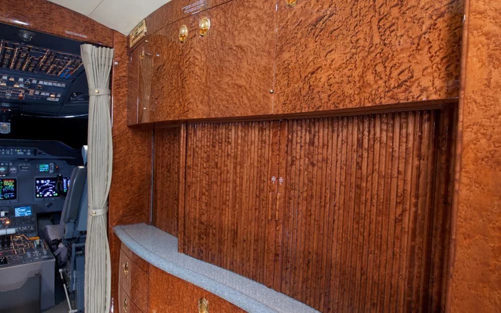 A detailed view of the aircraft's forward cabin or galley area with rich wood paneling, looking towards the cockpit.