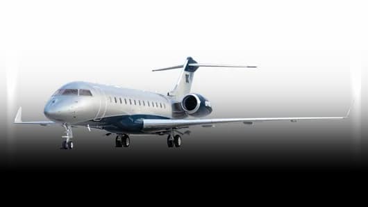 A silver and dark blue business jet, likely a Bombardier Challenger, viewed from the front-left against a white background.