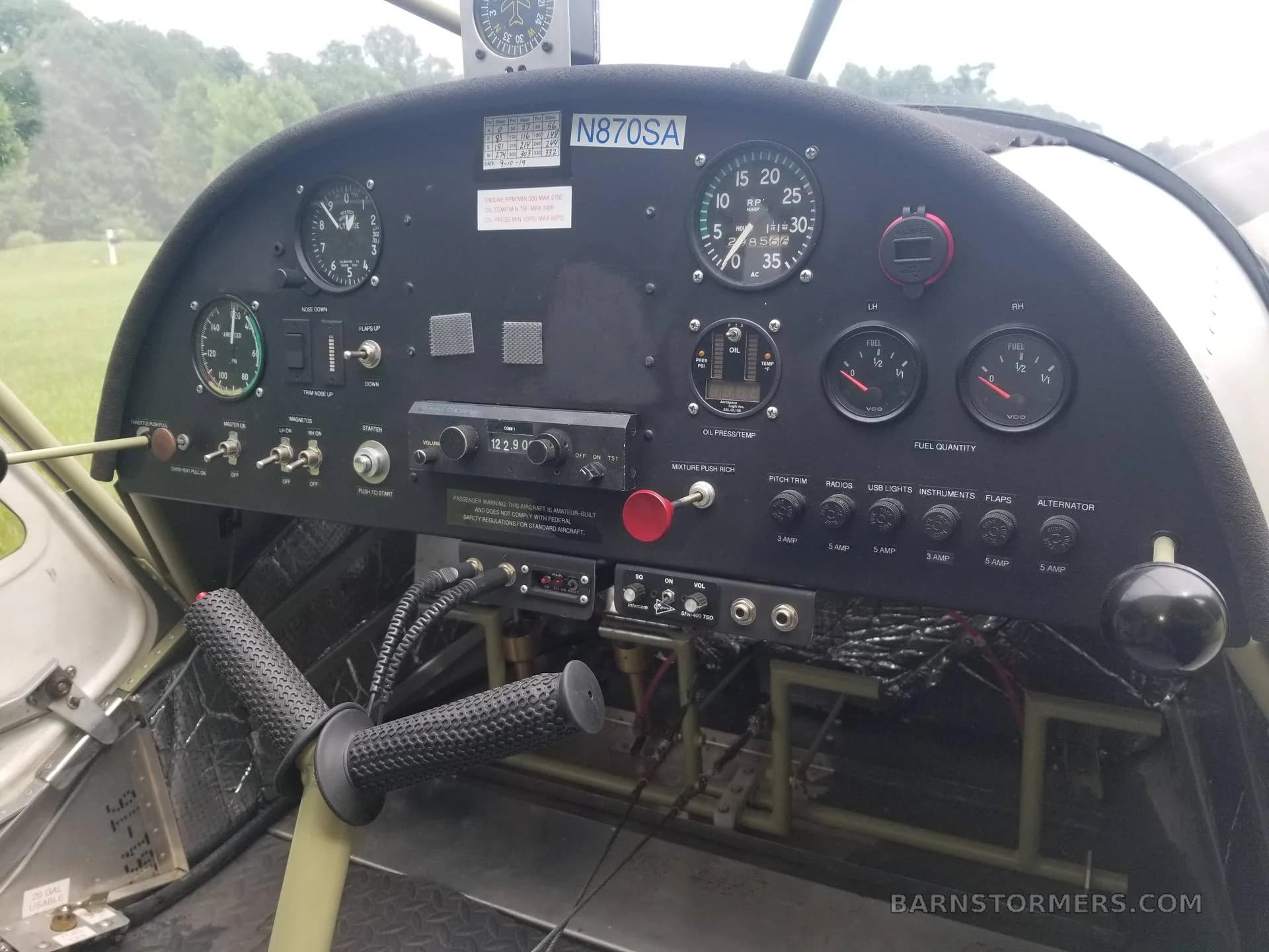 The cockpit of an ultralight aircraft, showing the instrument panel with gauges, switches, and a control yoke.
