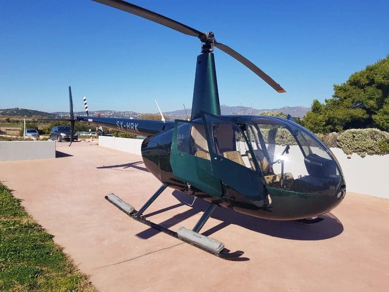 A Robinson R44 Clipper helicopter, registration SX-HRK, parked on a paved surface.