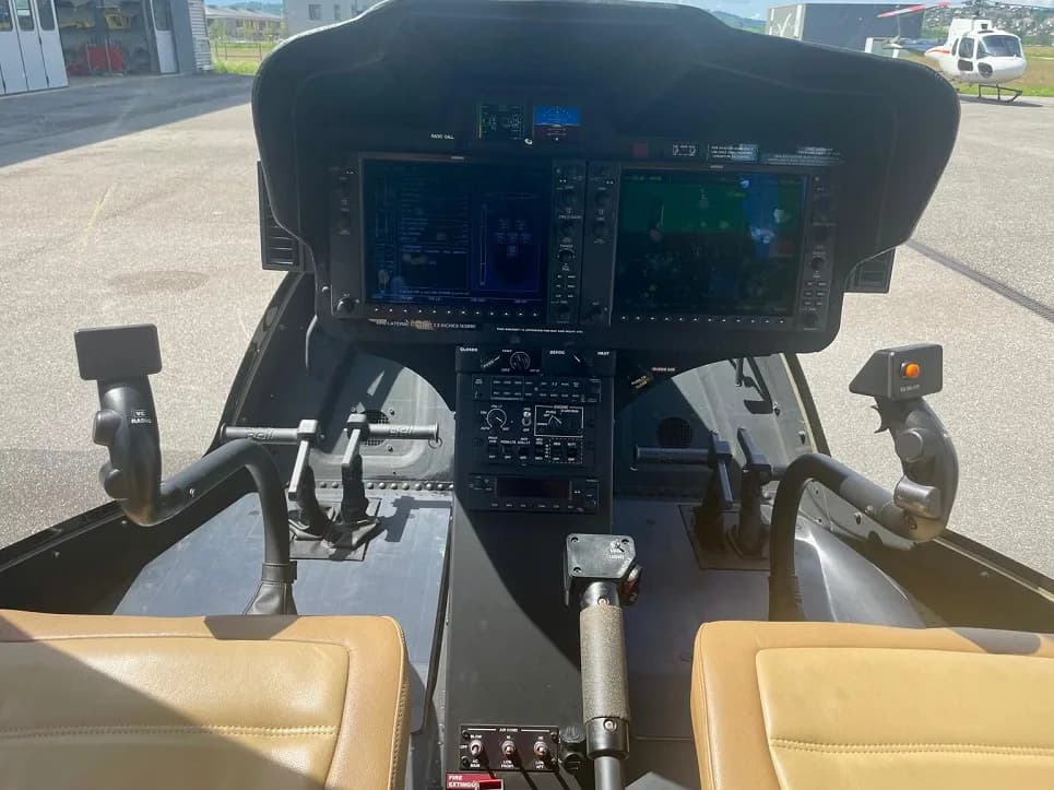 View of the helicopter cockpit with modern avionics and tan leather seats.