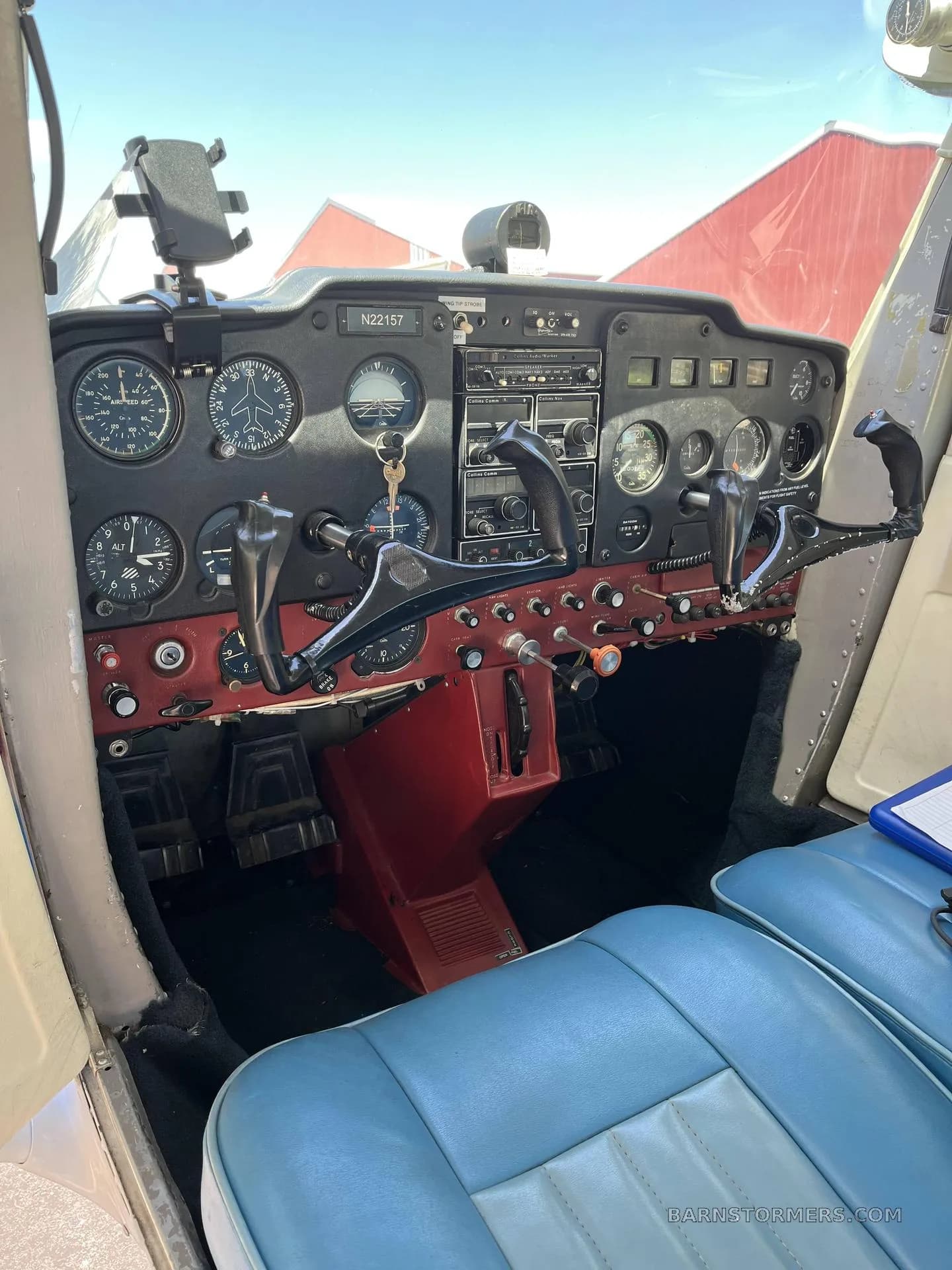 The cockpit of a Cessna 150/152 type aircraft with analog gauges, a red lower panel, and blue seats.