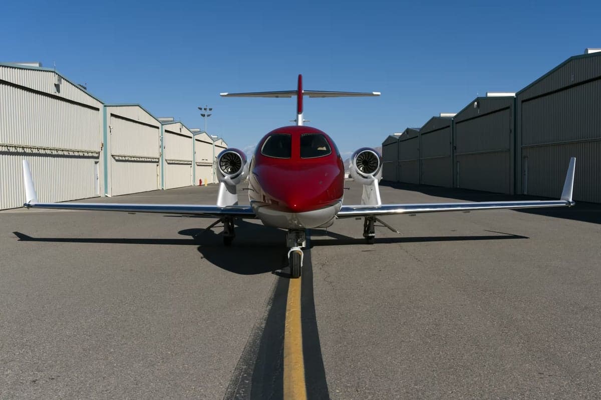Front view of a red and silver HondaJet parked on the tarmac.