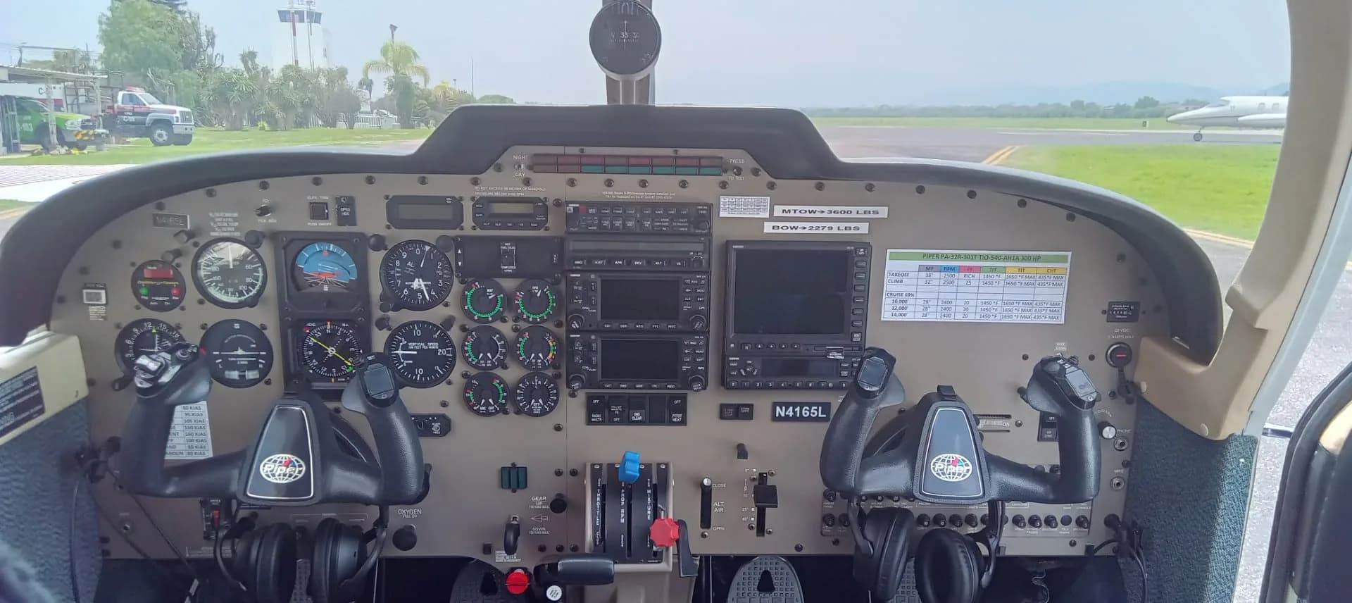 Full view of a small aircraft cockpit instrument panel with dual yokes and various gauges and screens.