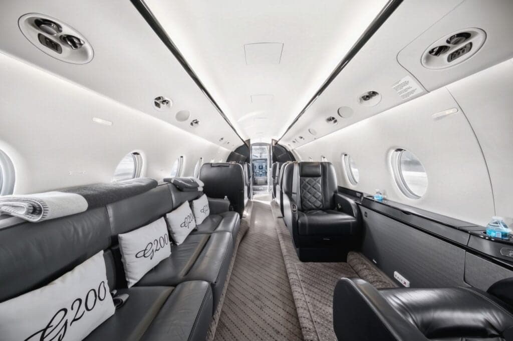 A view of the interior of the aircraft, showing the leather seats and a couch with pillows.