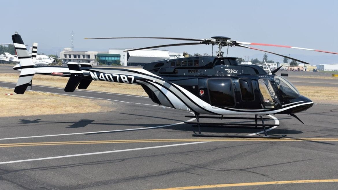 A black and silver Bell 407GX helicopter on the tarmac.