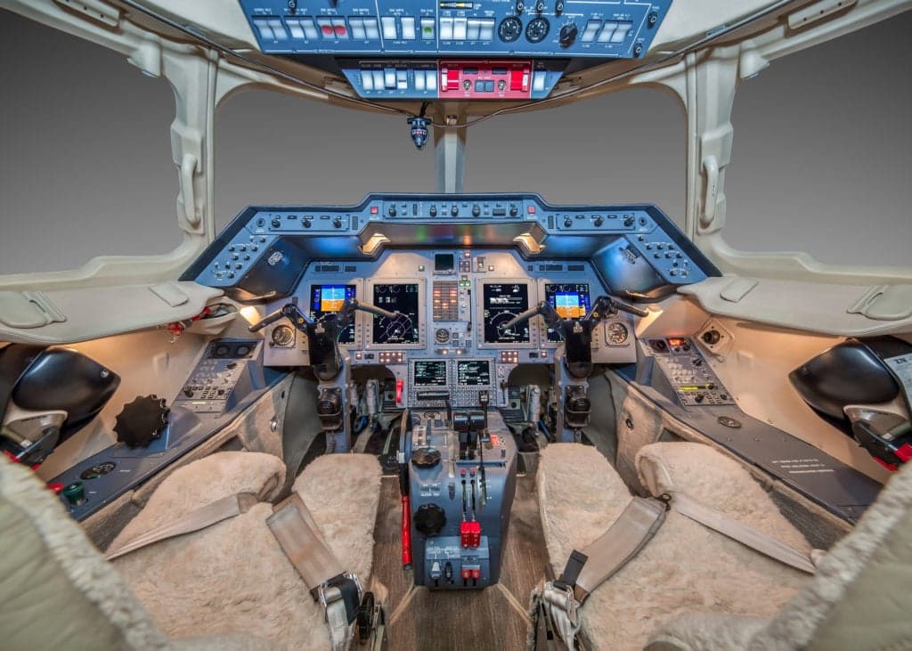 Close up of the aircraft's interior with leather seats, wood trim, and a table set for dining.