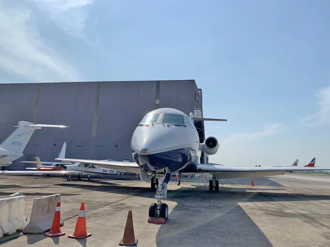 A Gulfstream G-IV business jet, registration N234LR, in a white and dark blue paint scheme, parked head-on in front of a hangar.