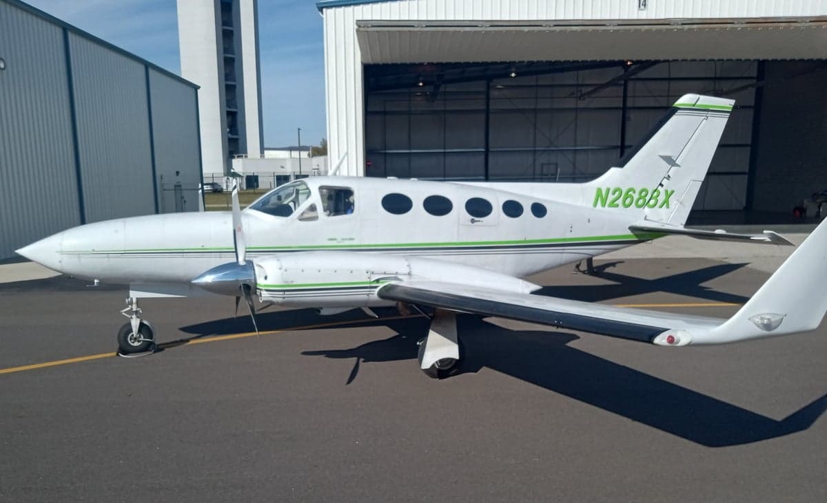 A white and green Cessna 414 with registration N268BX parked on the tarmac.
