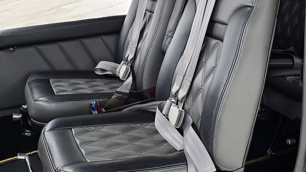 Close-up of the Cessna Caravan's leather passenger seats with diamond stitching and seatbelts.