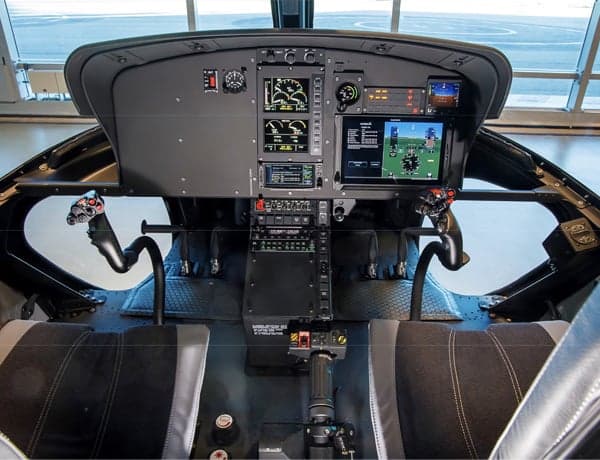 Helicopter cockpit instrument panel with flight controls and seats.