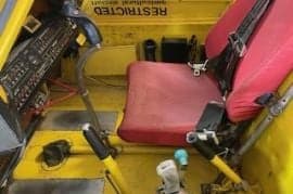 Cockpit view of an agricultural aircraft with a red seat.