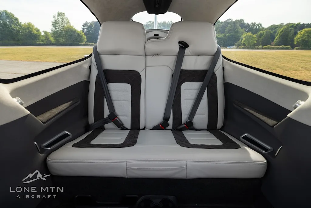 The light gray and black rear seats of an aircraft interior are shown.