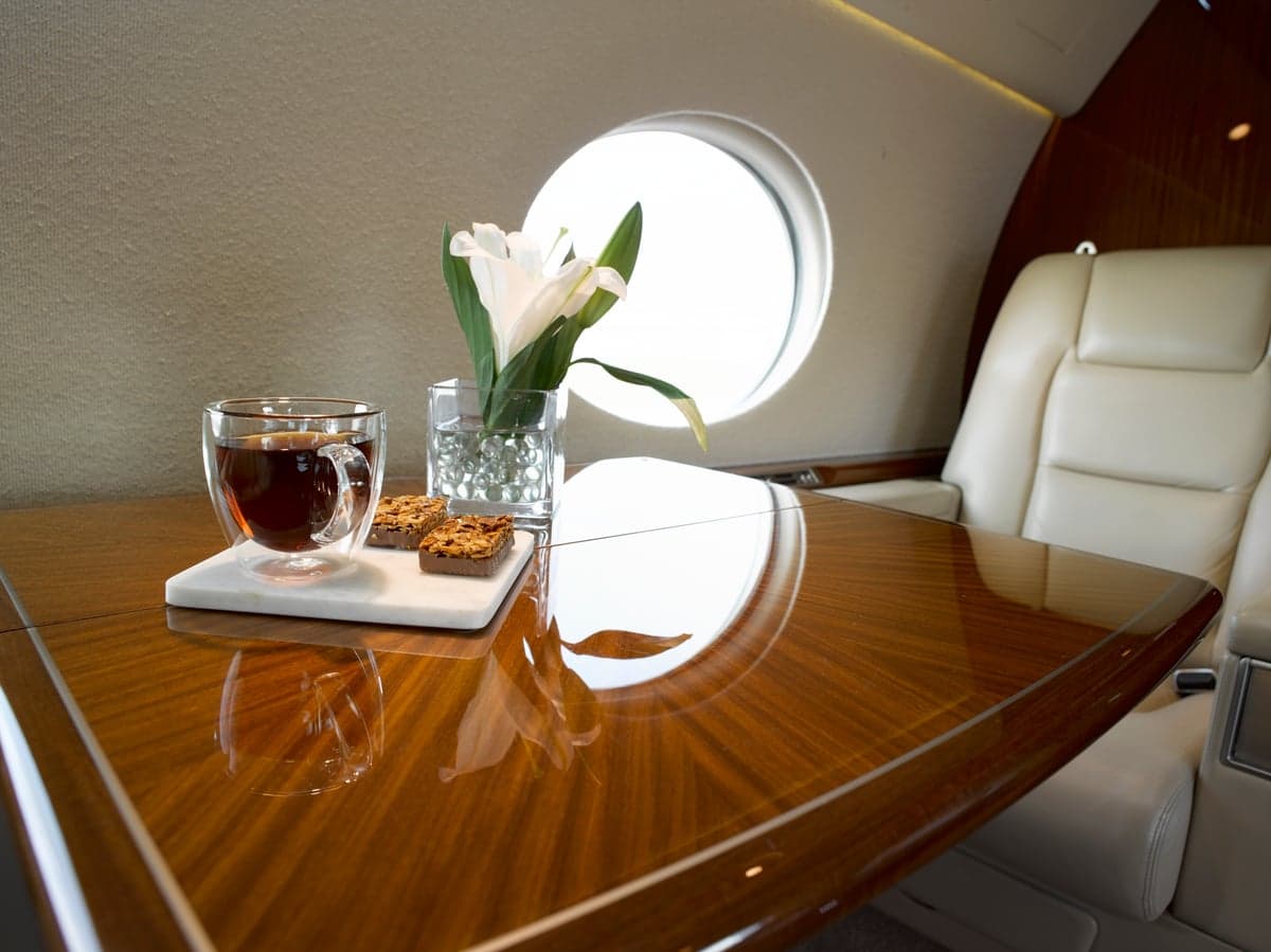 Close-up of a table in the aircraft's cabin with a drink, snacks, and flowers.