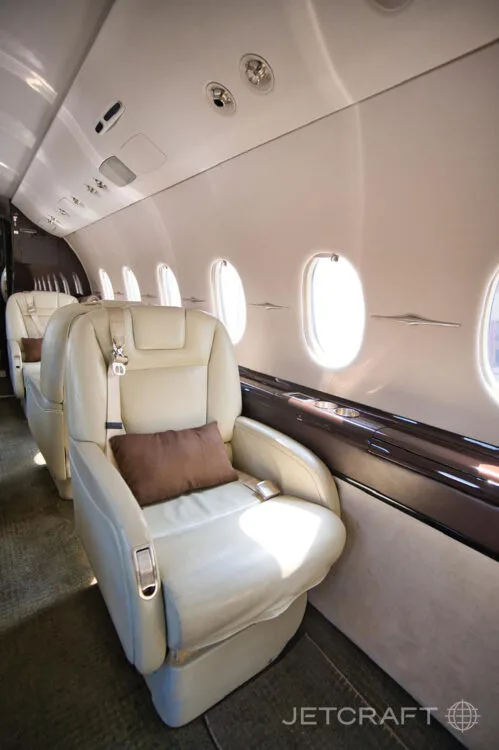 A view of the aircraft cabin showing a row of light-colored leather seats next to windows.