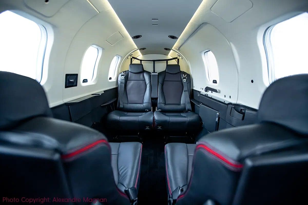 The interior cabin of an aircraft with black leather seats and white walls.