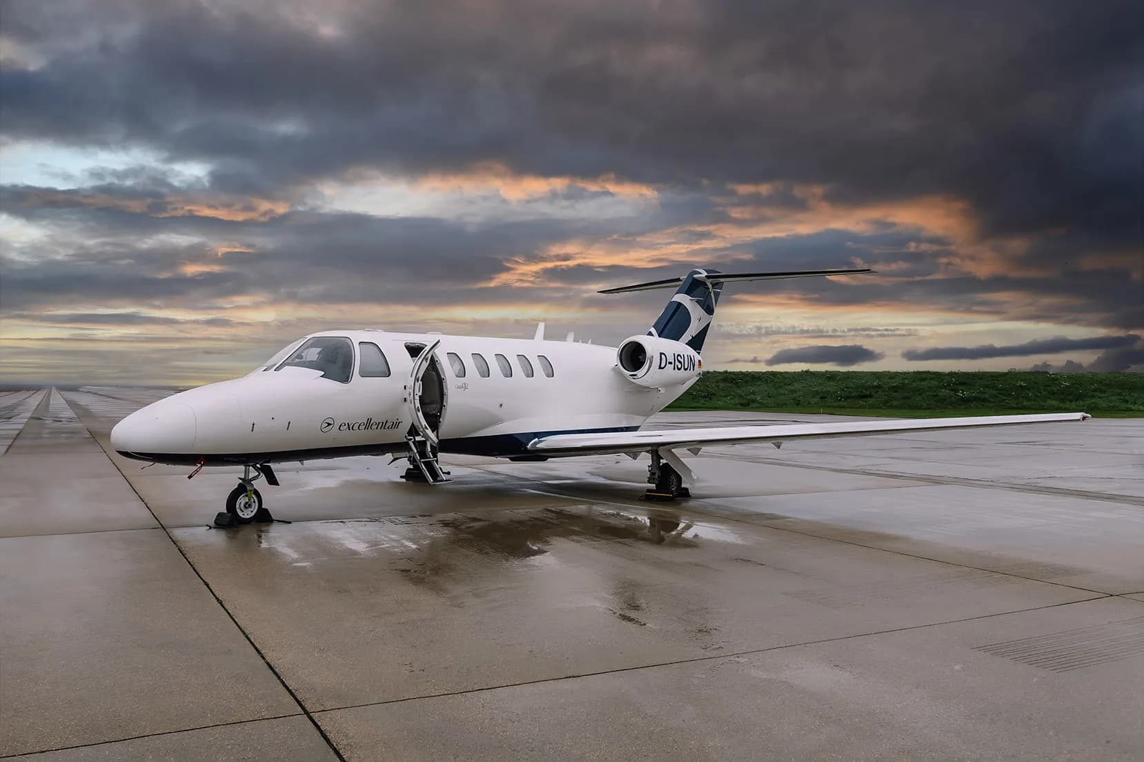 A Cessna Citation CJ2 aircraft with registration D-ISUN parked on the tarmac with the entry door open.