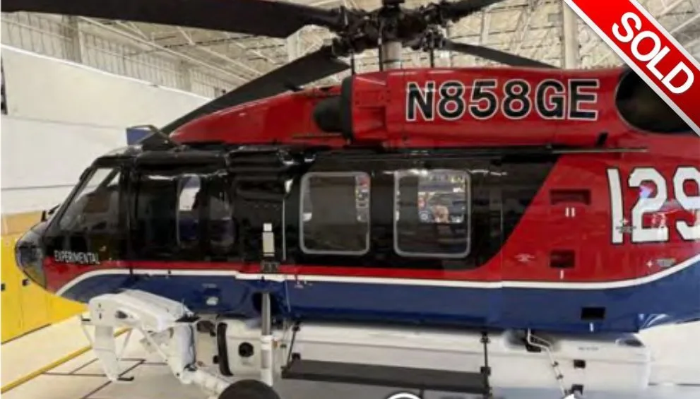 A red and blue experimental helicopter with registration N858GE, seen from the side in a hangar.