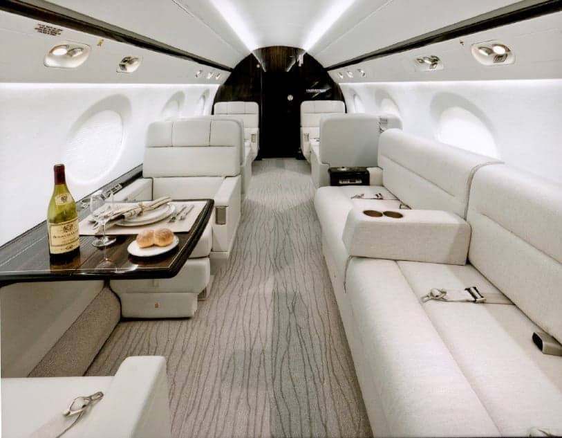 View of the interior cabin with white seats, tables, and a laptop.