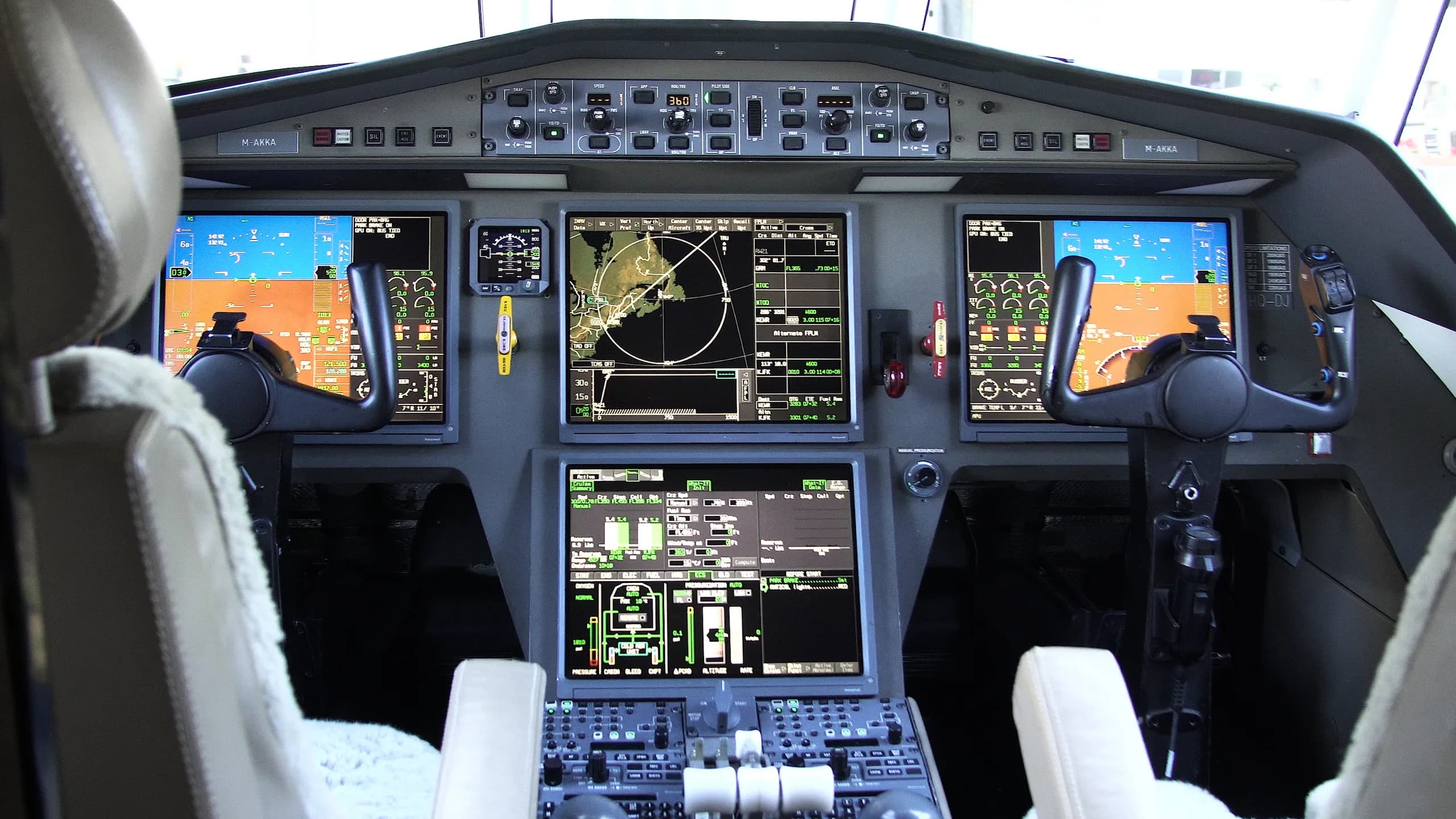 The modern cockpit of a business jet with multiple large digital displays and control yokes.
