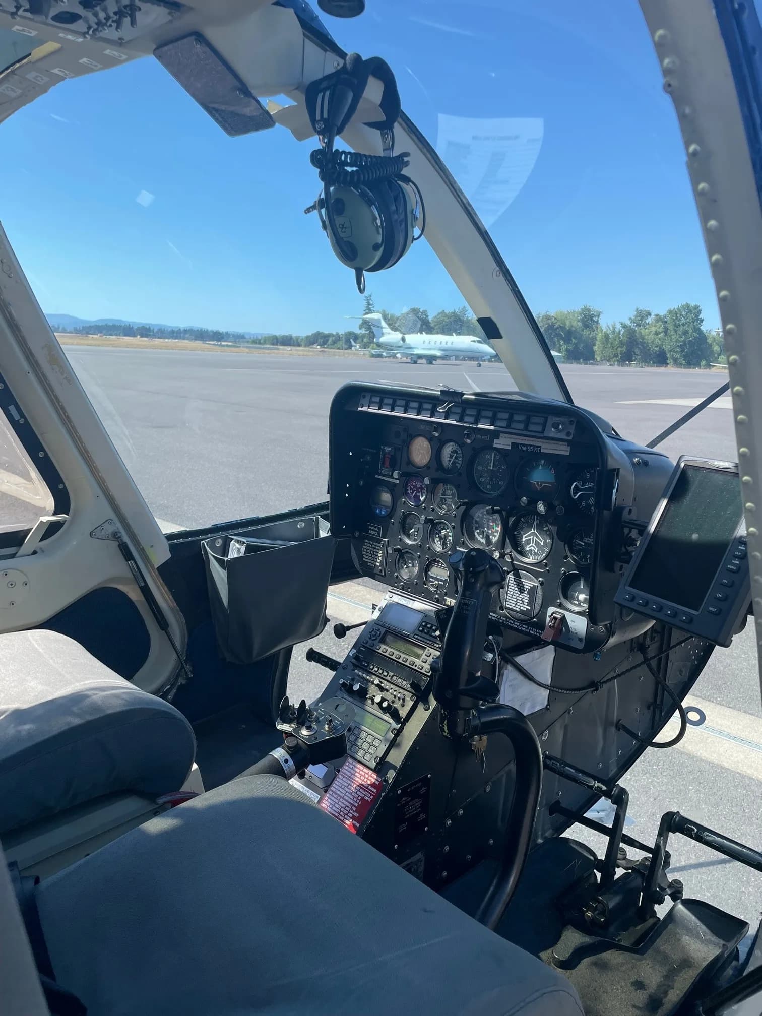 View of the cockpit of a Bell 206B Jet Ranger, looking out onto the runway.