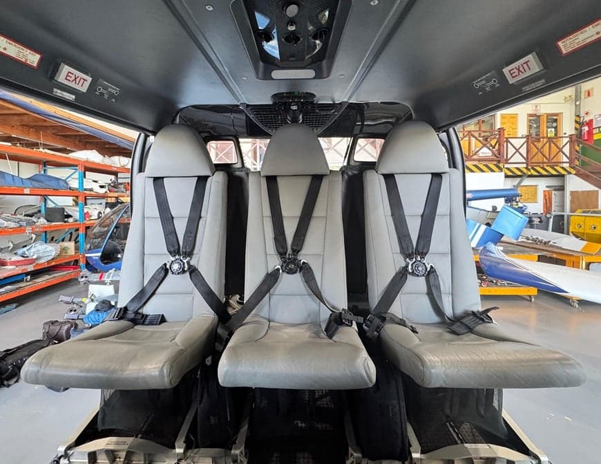 Rear cabin of the helicopter with three seats and seatbelts.