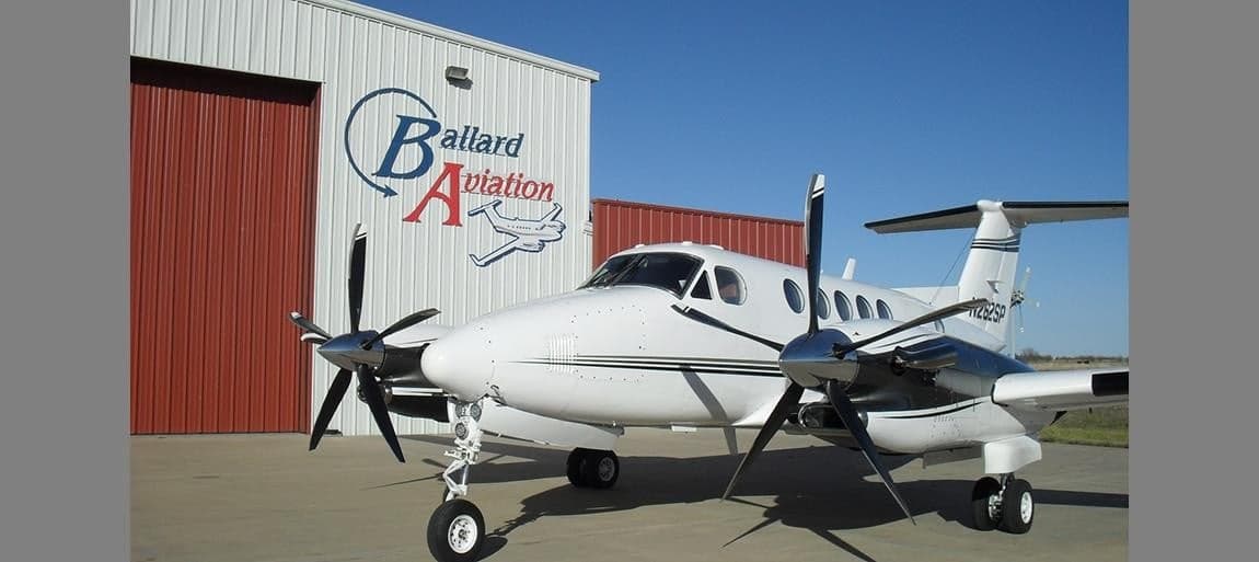 Front view of a King Air aircraft parked in front of a hangar.