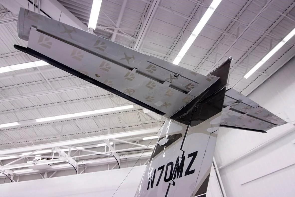 A close-up view of the T-tail and vertical stabilizer of the Cessna Citation M2 jet (N70MZ) inside a hangar.