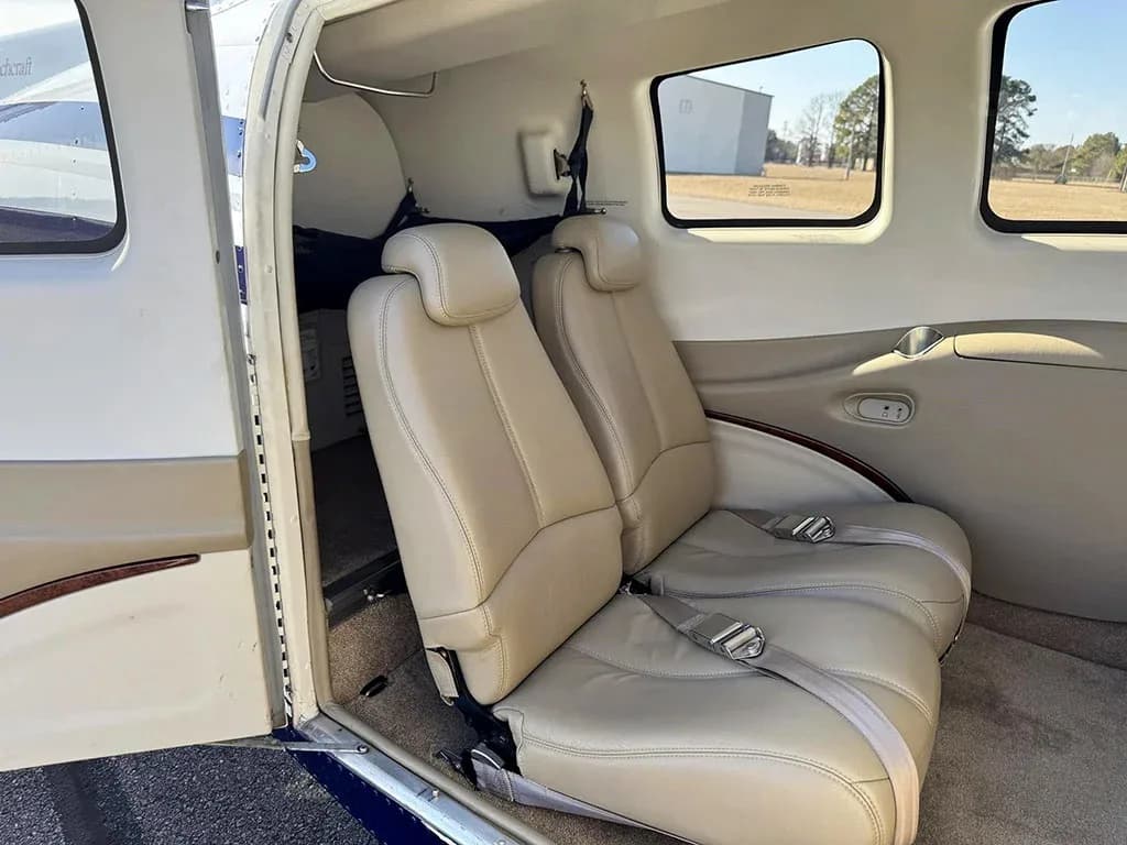 Two tan leather passenger seats in the aircraft cabin, viewed from the open door.